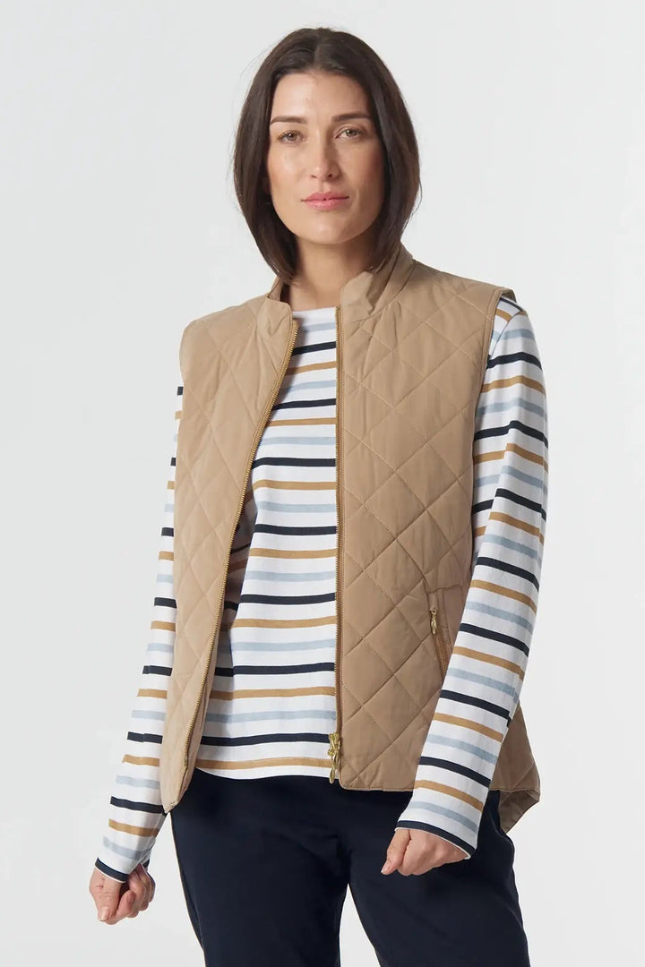 Woman wearing a striped shirt, beige vest, and dark pants on a white background