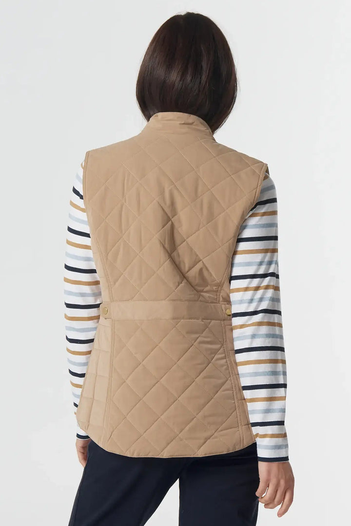 Person wearing a beige quilted vest over a striped shirt with navy pants on a white background