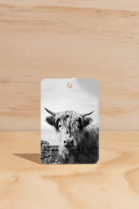 Cardboard tag with a black and white photo of a cow on a wooden surface