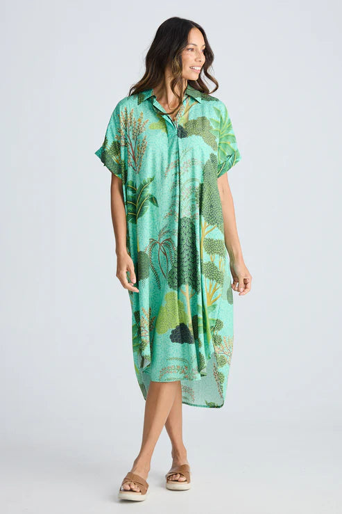 Woman wearing a green floral dress on a white background. Holiday Trading Canal Overshirt Rainforest Print