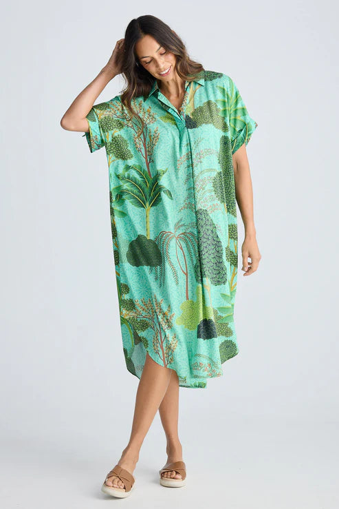 Woman wearing a green tropical patterned dress on a white background. Holiday Trading Canal Overshirt Rainforest Print