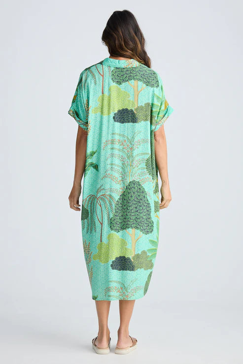 Woman wearing a green patterned dress on a white background. Holiday Trading Canal Overshirt Rainforest Print