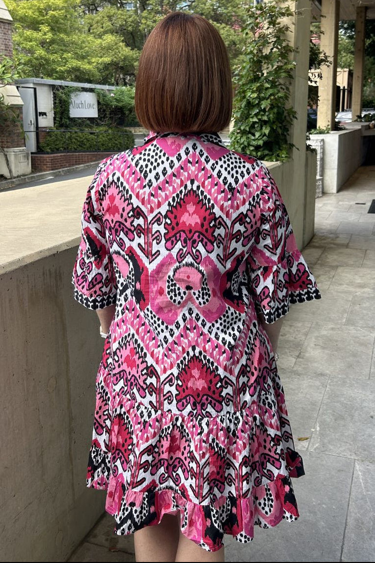 Person wearing a pink and black patterned dress in an urban setting