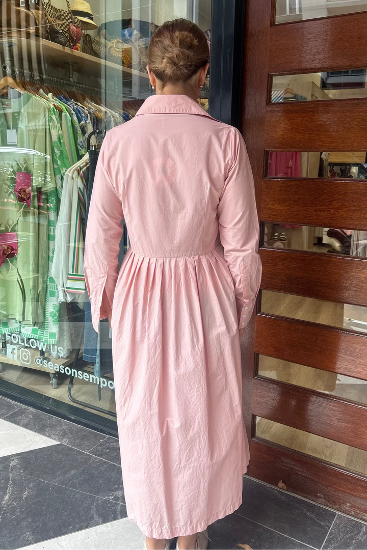 Person wearing a pink dress standing in front of a store window display.