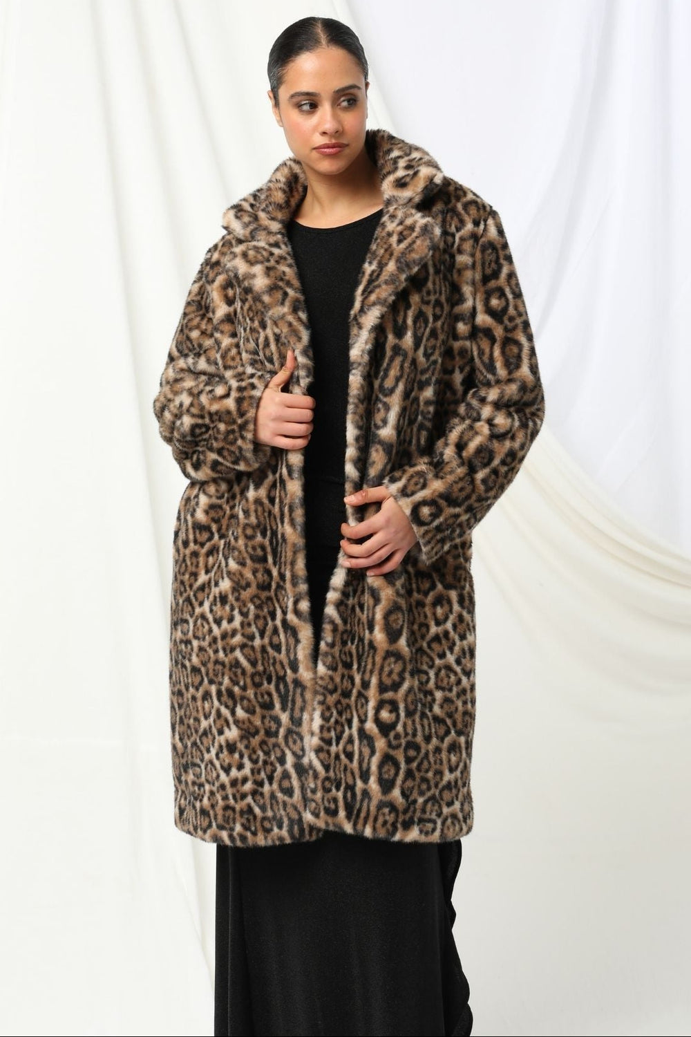 Person wearing a leopard print coat against a white background