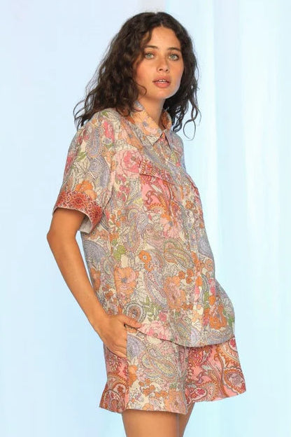 Woman wearing a floral dress against a light blue background. Kachel Isla Shirt