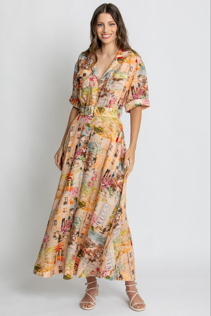 A woman modeling a long-sleeved maxi dress with a multicolor vintage map and floral collage print on a beige background, paired with beige strappy sandals, against a light gray studio backdrop.