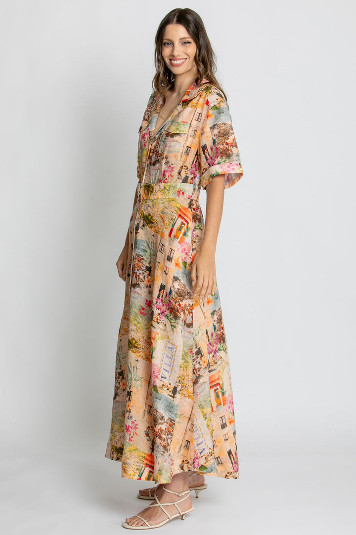 A woman modeling a long-sleeved maxi dress with a colorful vintage collage print on a light beige background, paired with beige strappy flat sandals, against a light gray studio background.