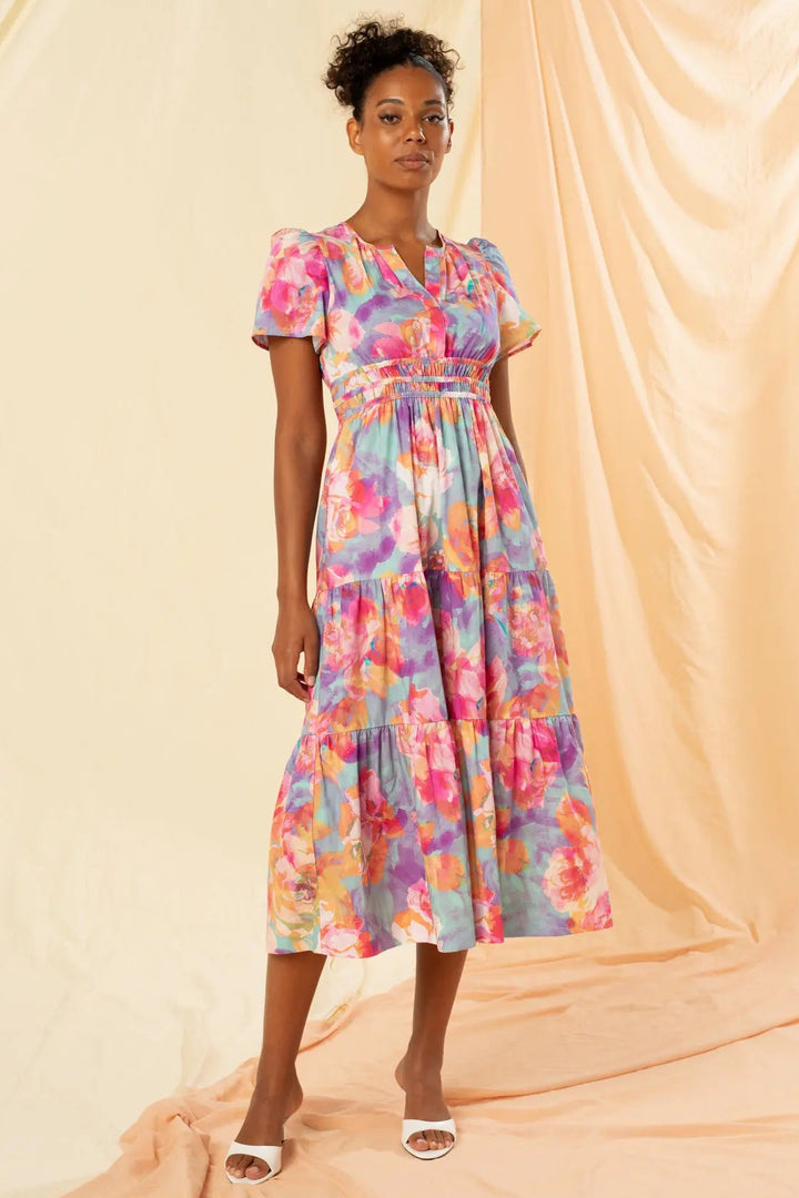 Woman wearing a colorful floral dress against a beige background