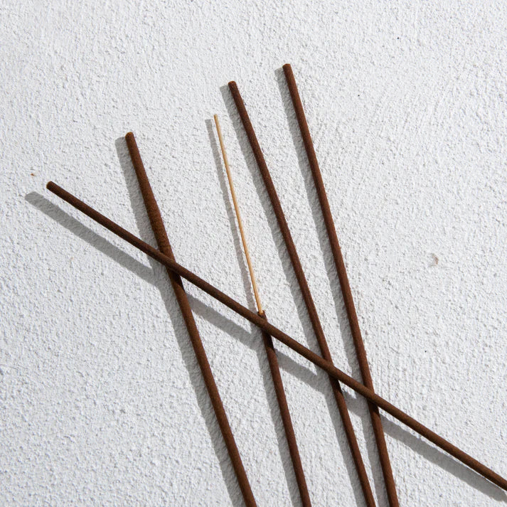 Five incense sticks on a textured white surface