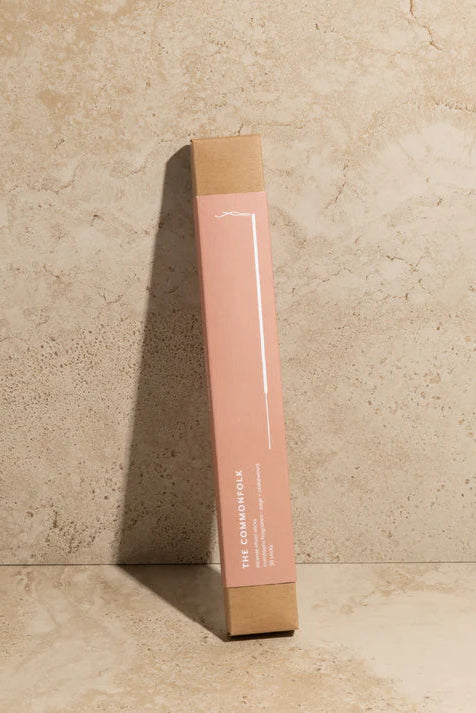 Pink cylindrical product packaging with cardboard base on a beige stone background