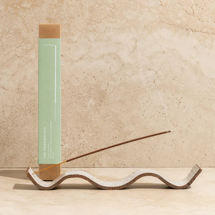 Incense stick with a wooden holder on a beige surface