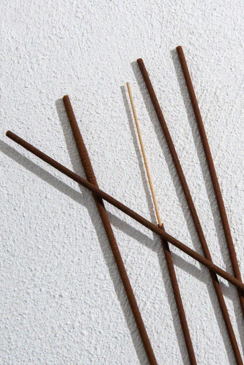 Five incense sticks on a textured white surface