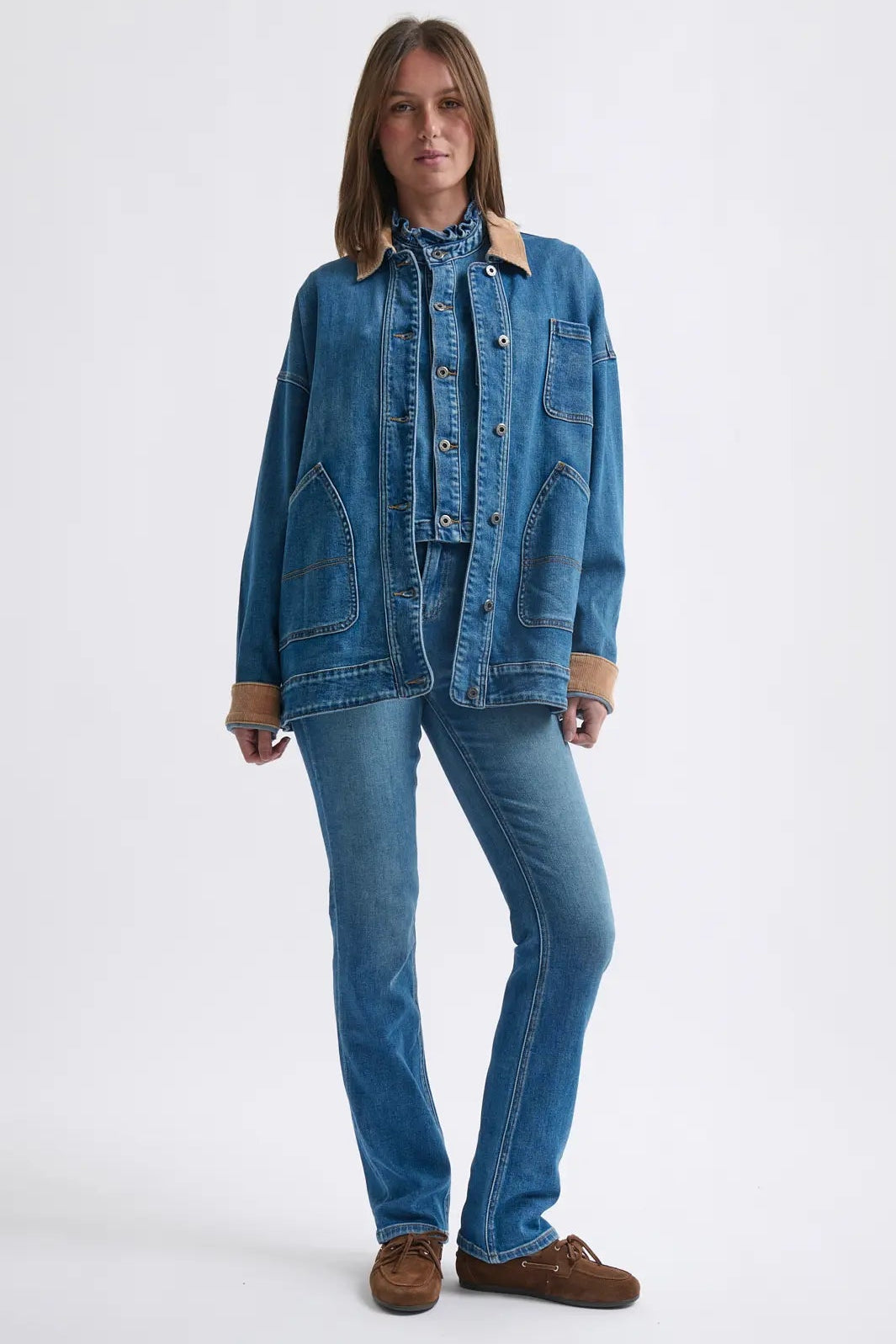 Person wearing a blue denim jacket and jeans on a white background