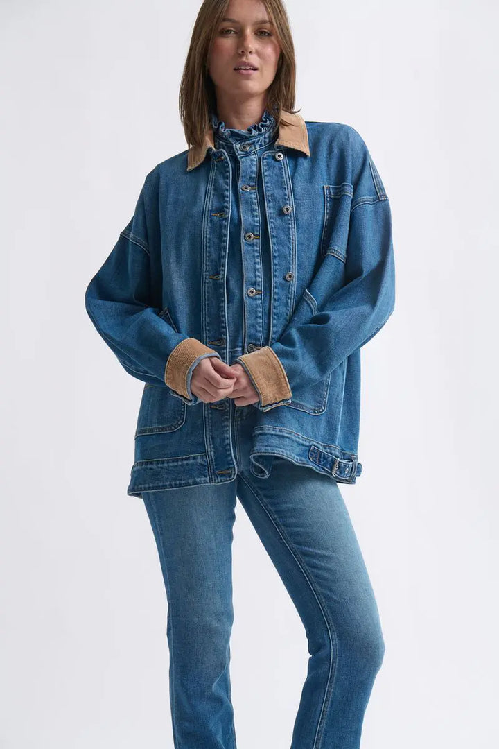 Woman wearing a blue denim jacket with beige trim on a white background