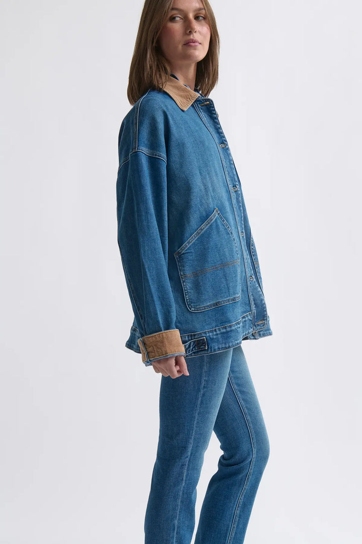 Person wearing a blue denim jacket and jeans on a white background