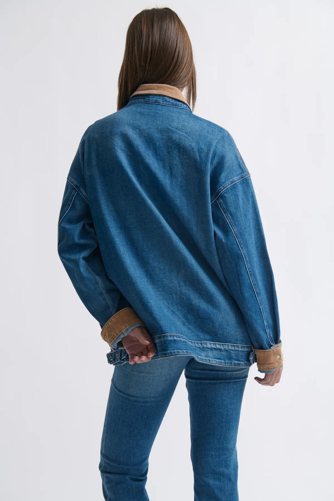 Person wearing a blue denim jacket and jeans on a white background