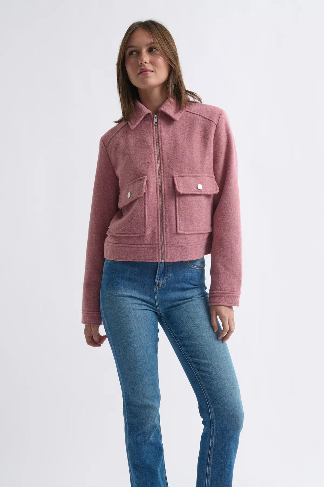 Woman wearing a pink jacket and blue jeans on a white background
