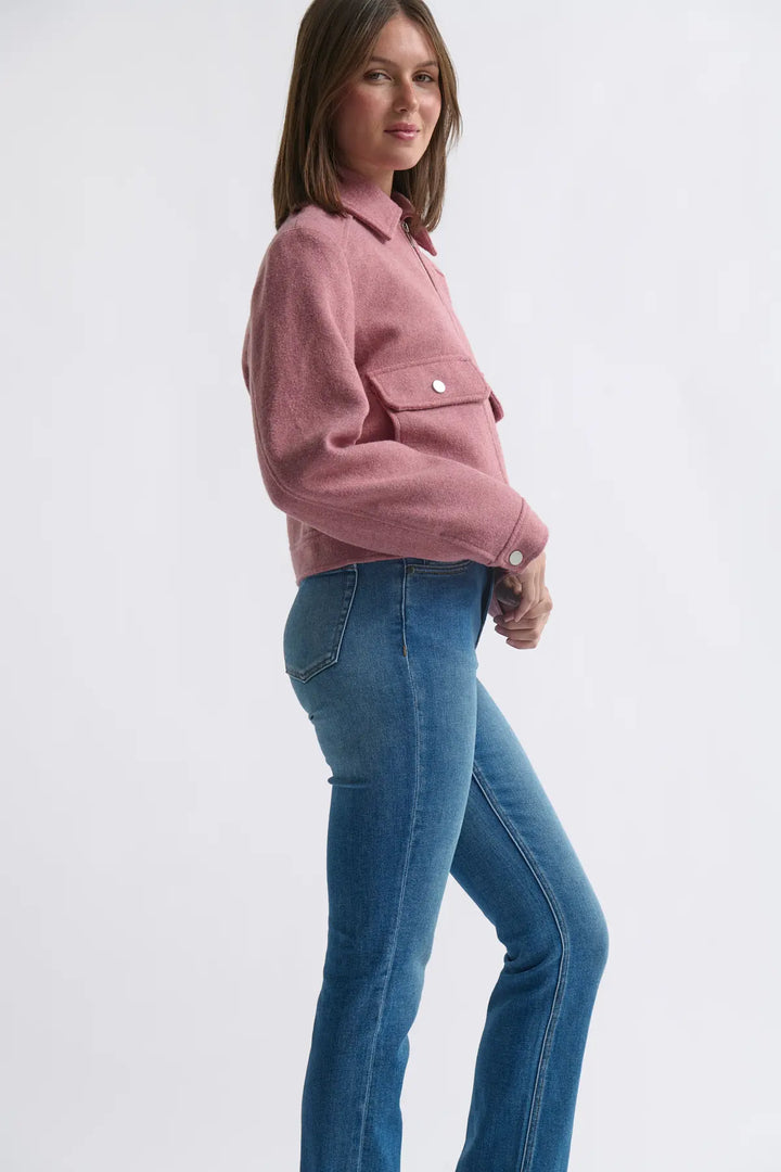 Woman wearing a pink jacket and blue jeans on a white background