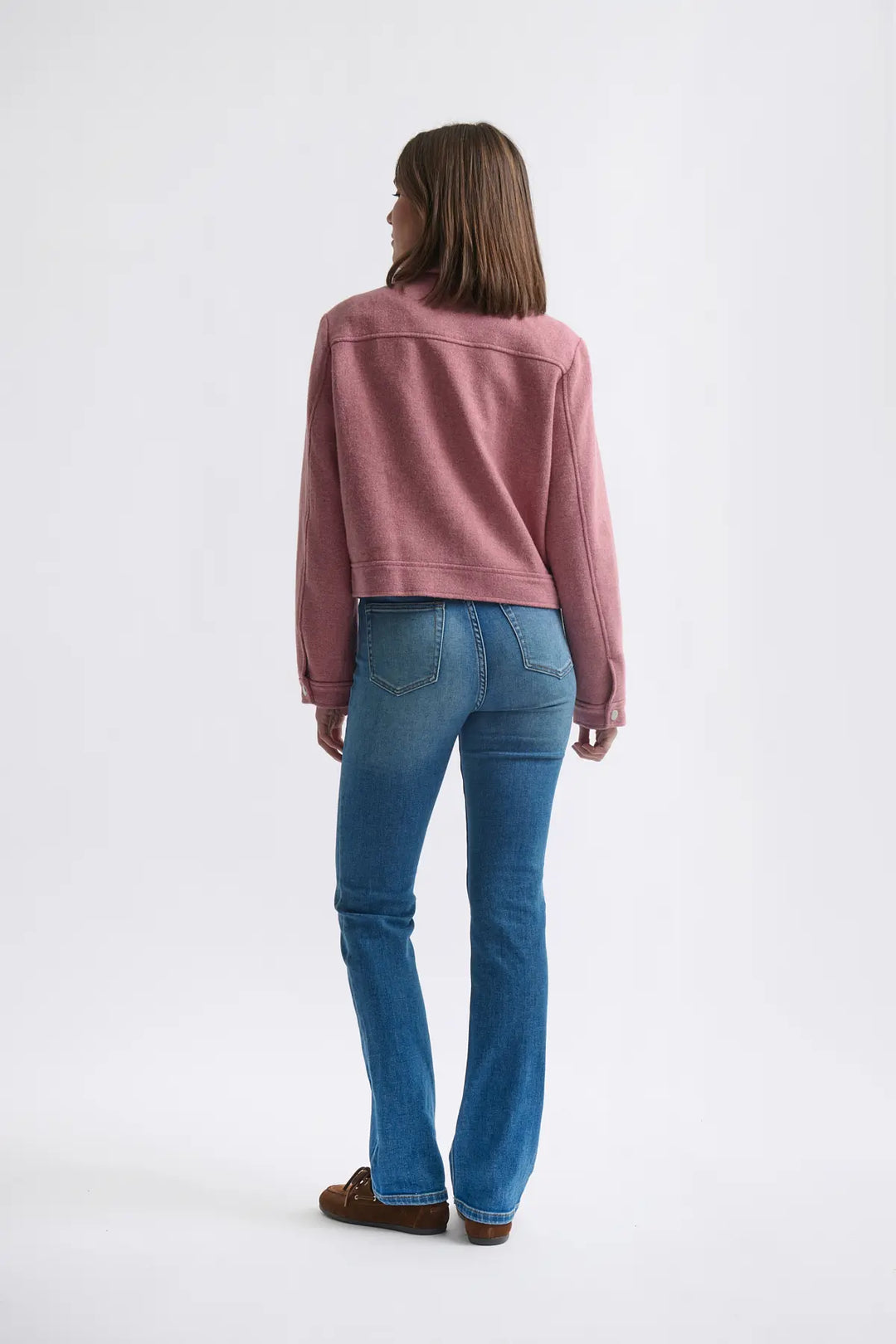 Person wearing a pink sweater and blue jeans on a white background