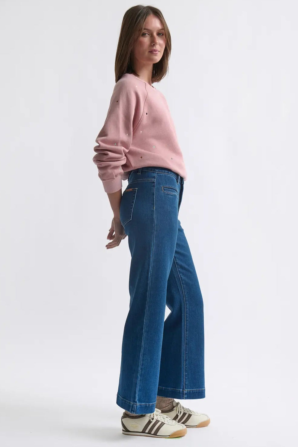 Woman wearing a pink sweater and blue jeans on a white background