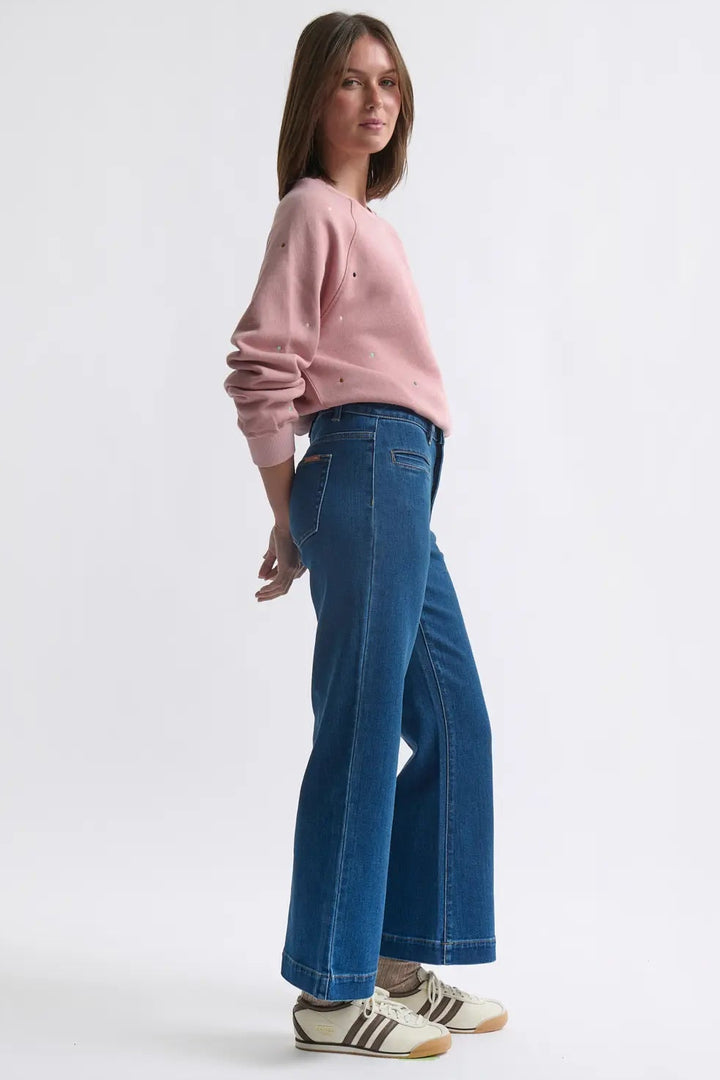 Woman wearing a pink sweater and blue jeans on a white background