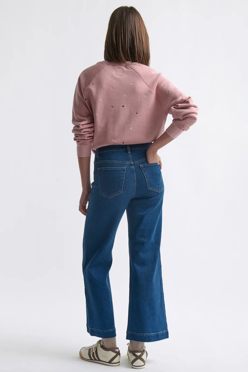Person wearing a pink sweater and blue jeans on a white background