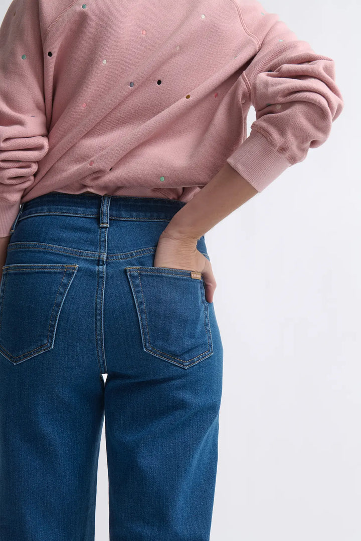 Person wearing a pink sweatshirt and blue jeans on a white background