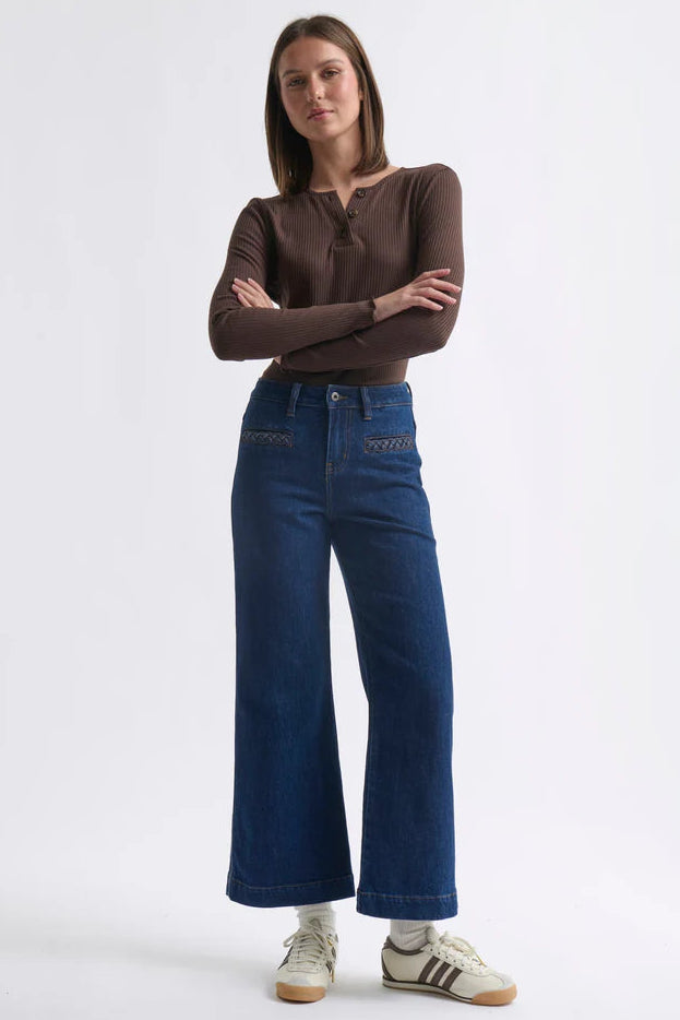 Woman wearing a brown top and blue jeans on a white background