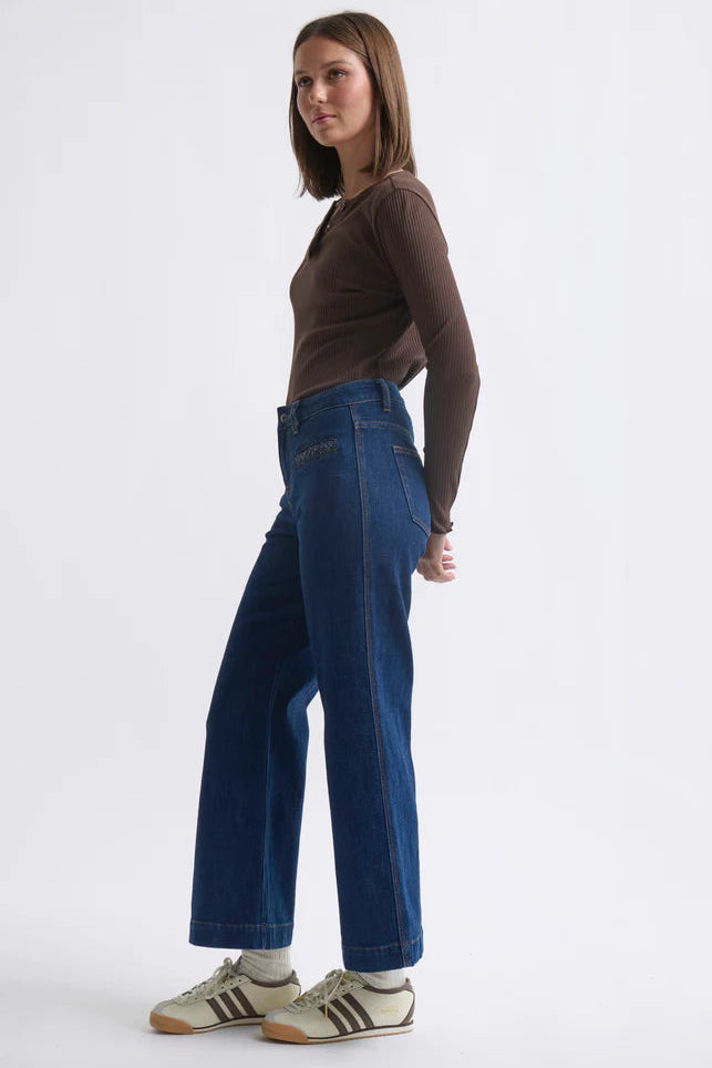 Woman wearing blue jeans and a brown top on a white background