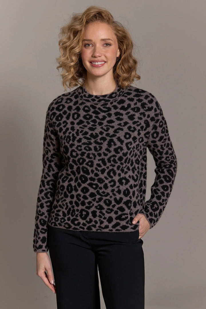 Woman wearing a leopard print sweater against a plain background