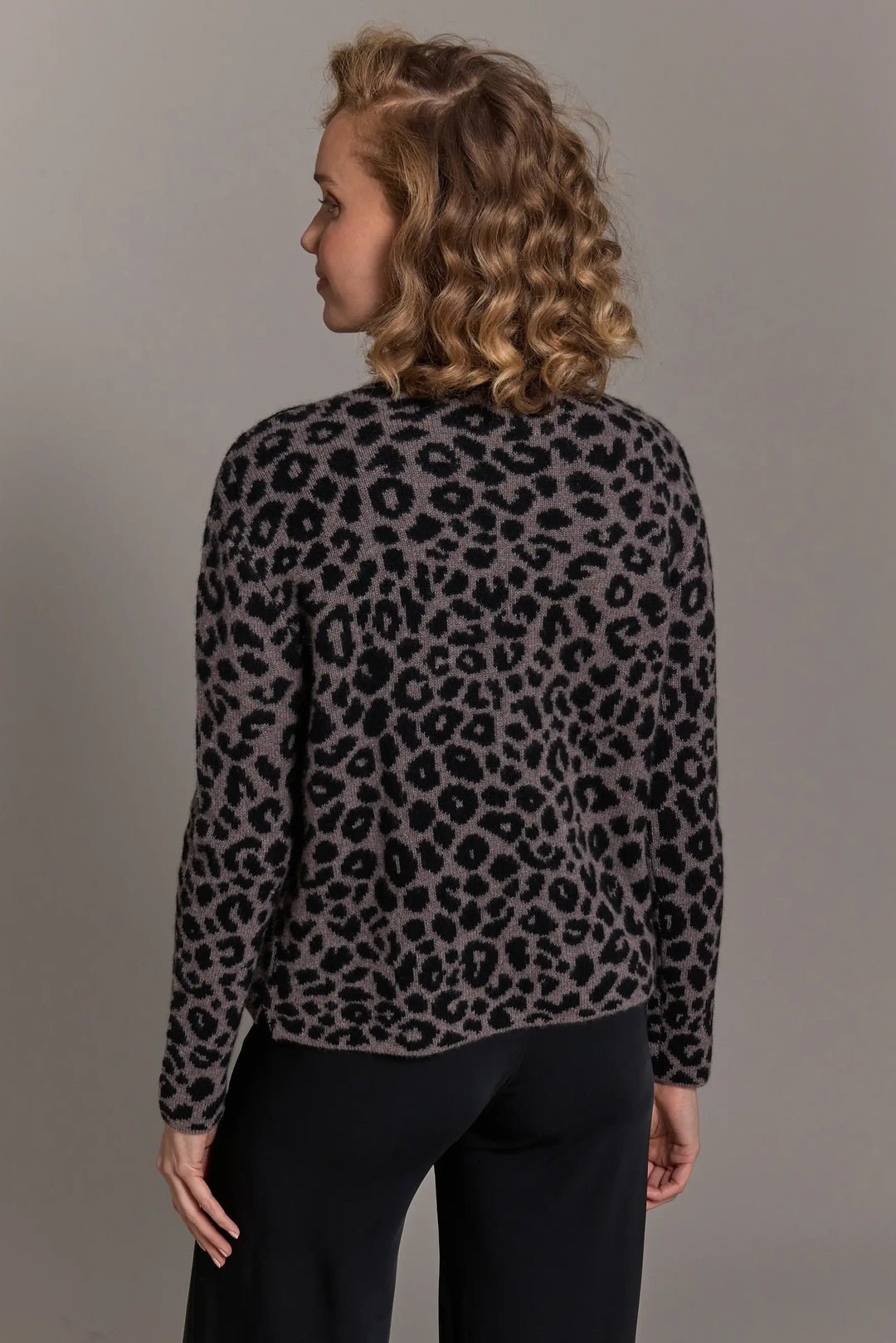 Person wearing a leopard print sweater against a plain background