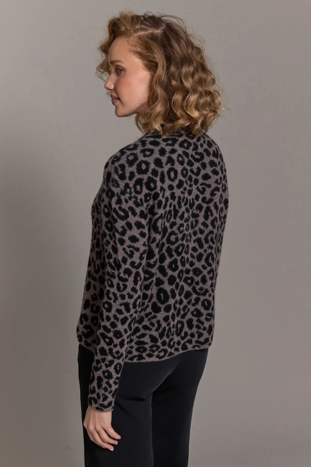 Woman wearing a leopard print sweater against a plain background