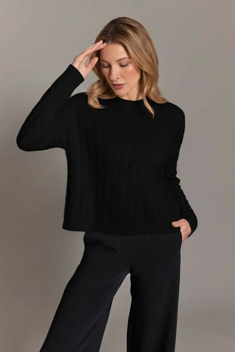Woman wearing a black sweater and pants against a plain background