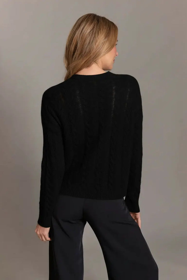 Person wearing a black sweater and pants against a gray background