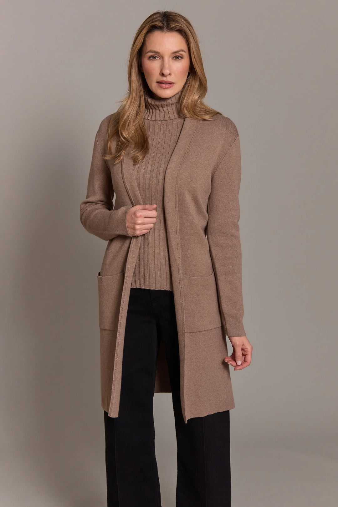 Woman wearing a long brown cardigan against a plain background
