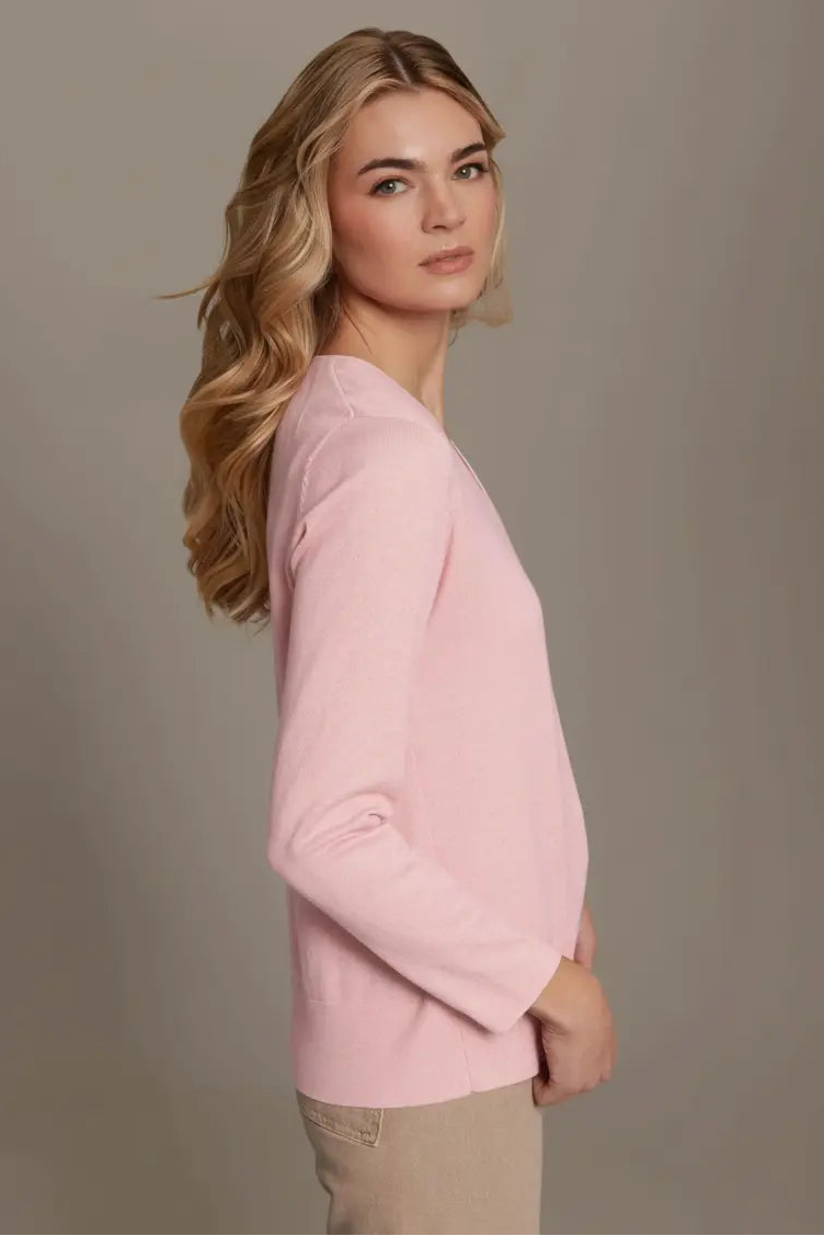 Woman wearing a pink sweater against a plain background