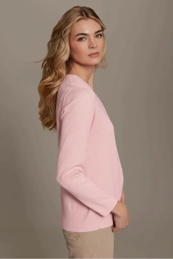 Woman wearing a pink sweater against a plain background