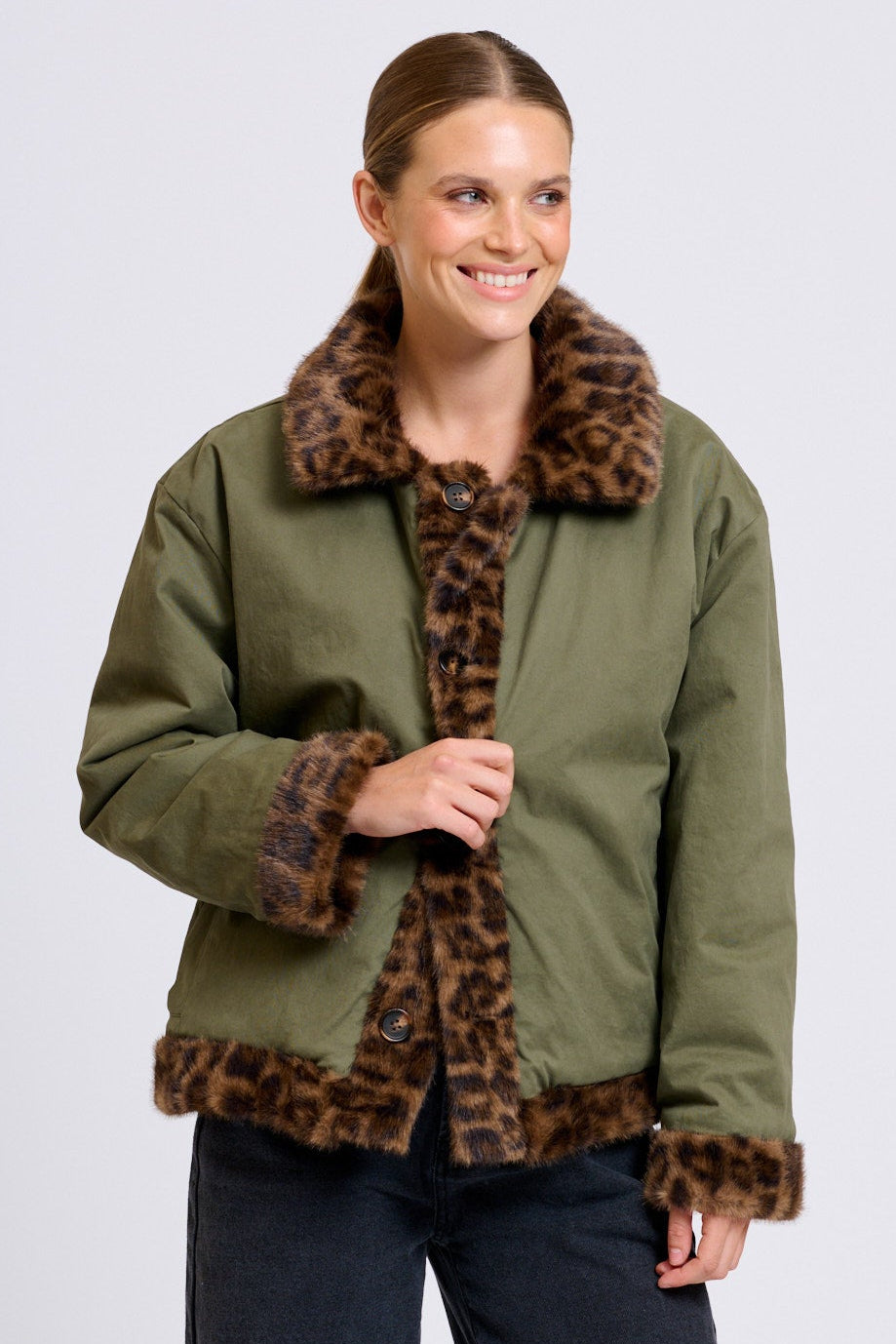 Woman wearing a green jacket with a leopard print collar on a white background