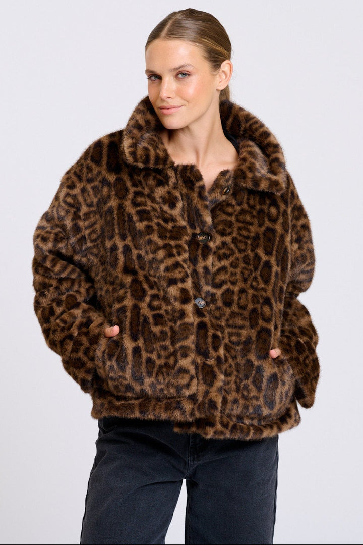 Woman wearing a leopard print jacket on a plain background