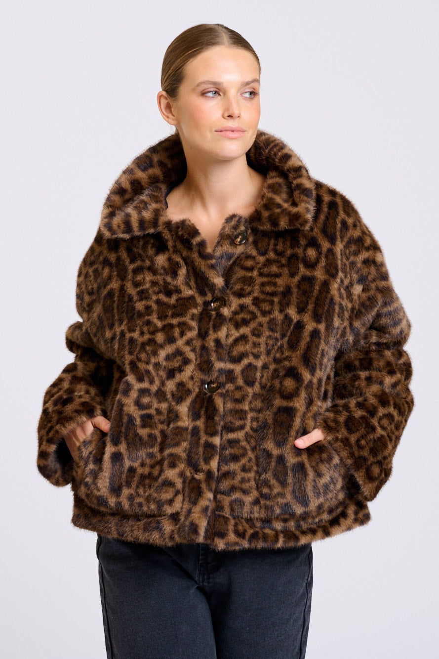Woman wearing a leopard print jacket on a plain background