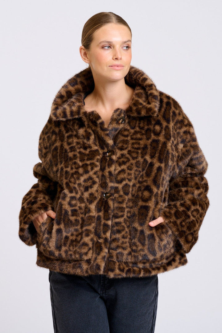 Woman wearing a leopard print jacket on a plain background