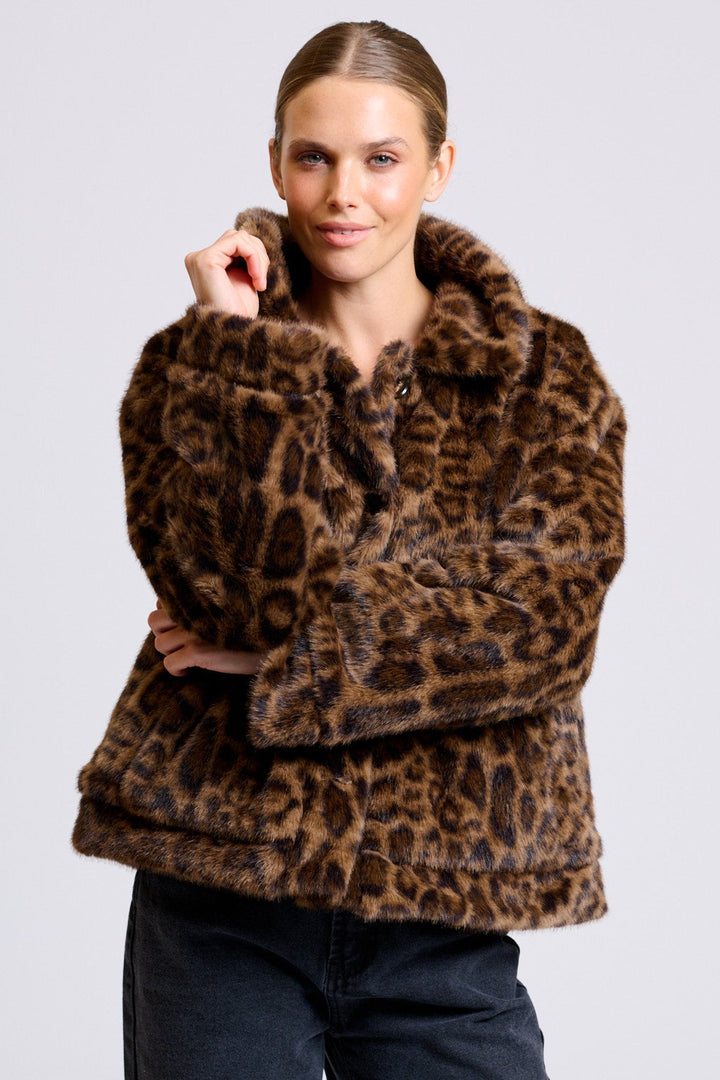 Woman wearing a leopard print coat against a plain background