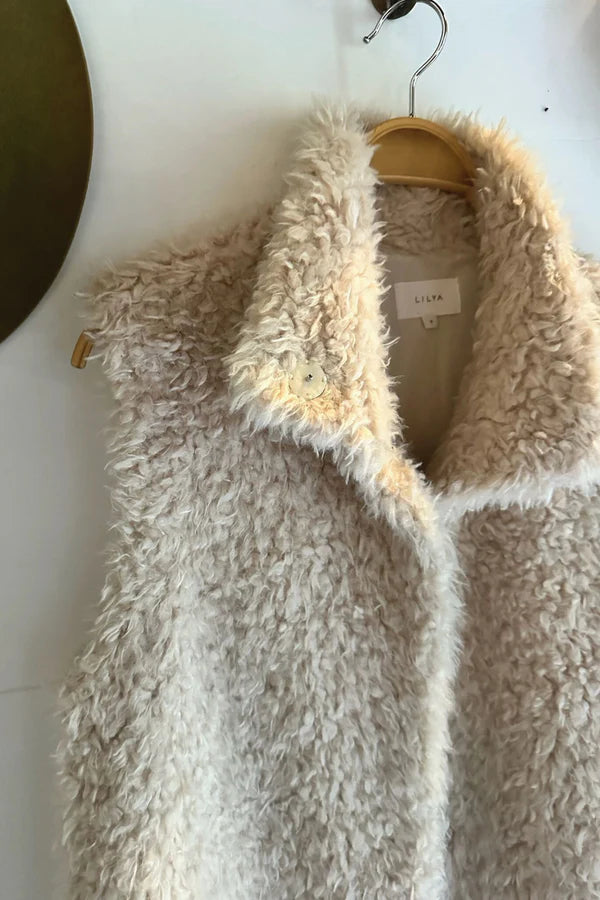 Beige fluffy vest on a hanger against a white background