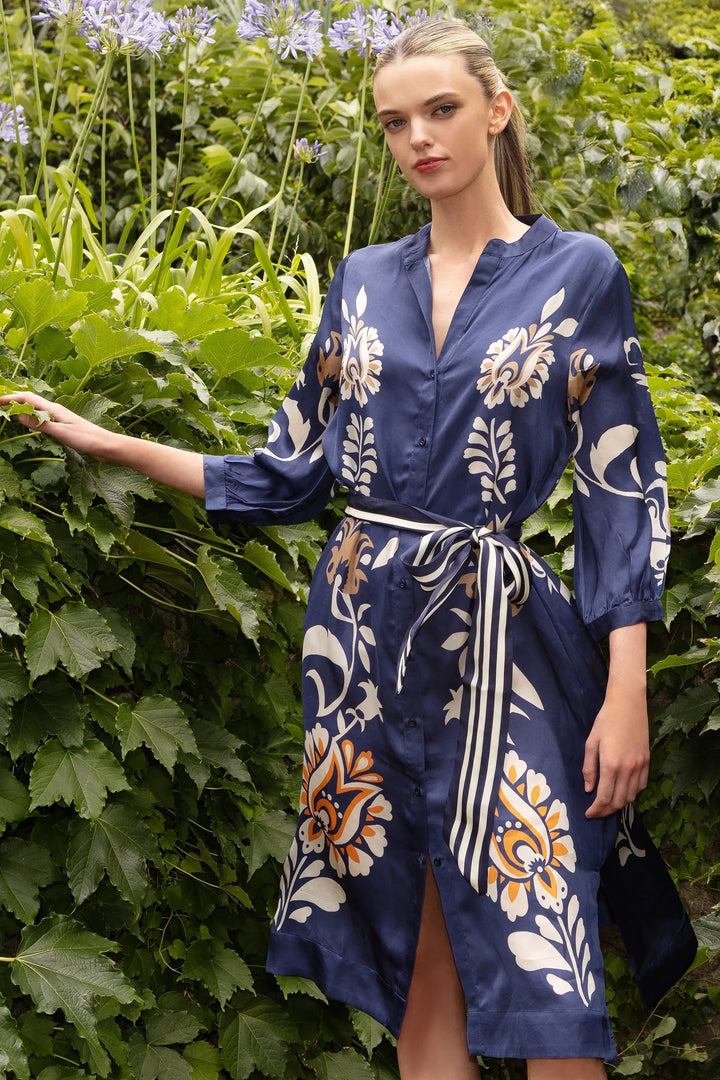 Woman in a blue floral dress standing among green plants