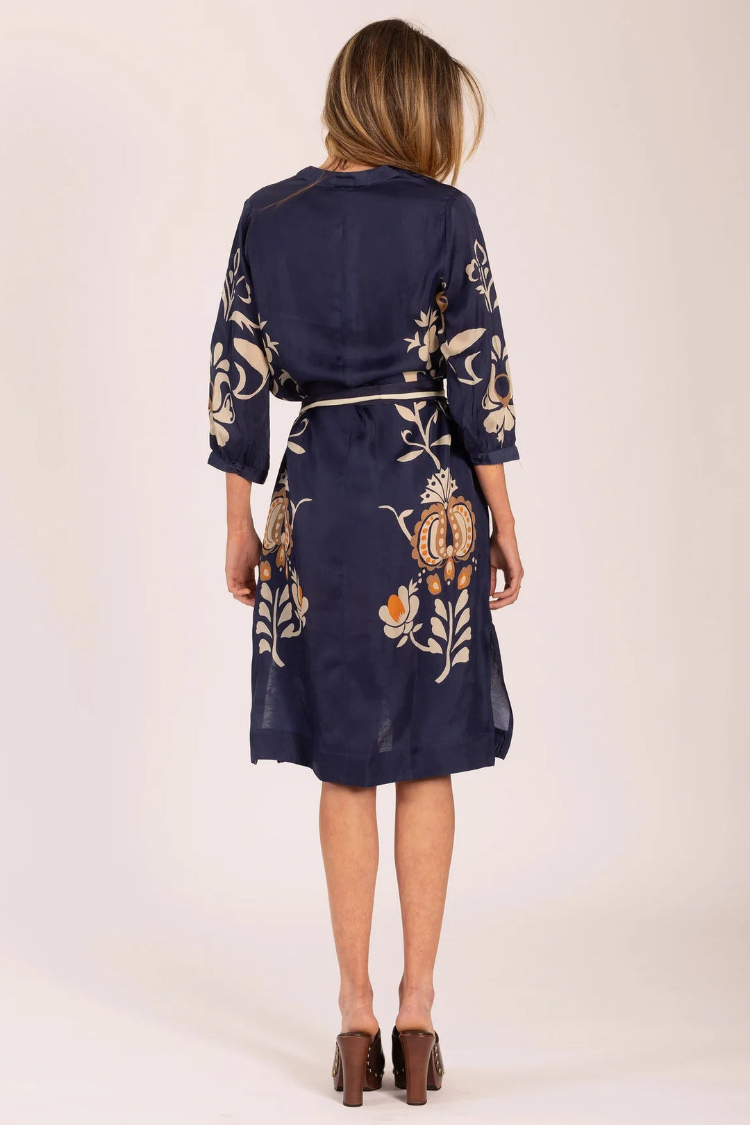 Woman wearing a navy dress with floral patterns on a beige background