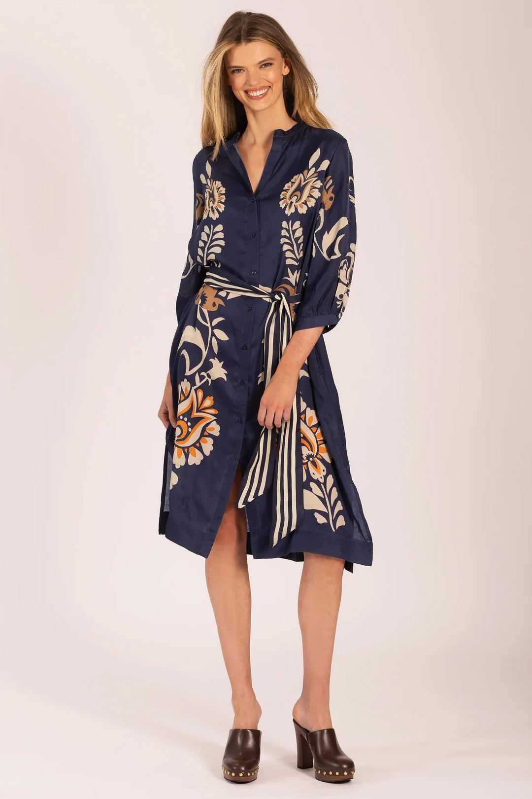 Woman wearing a navy dress with floral patterns on a white background