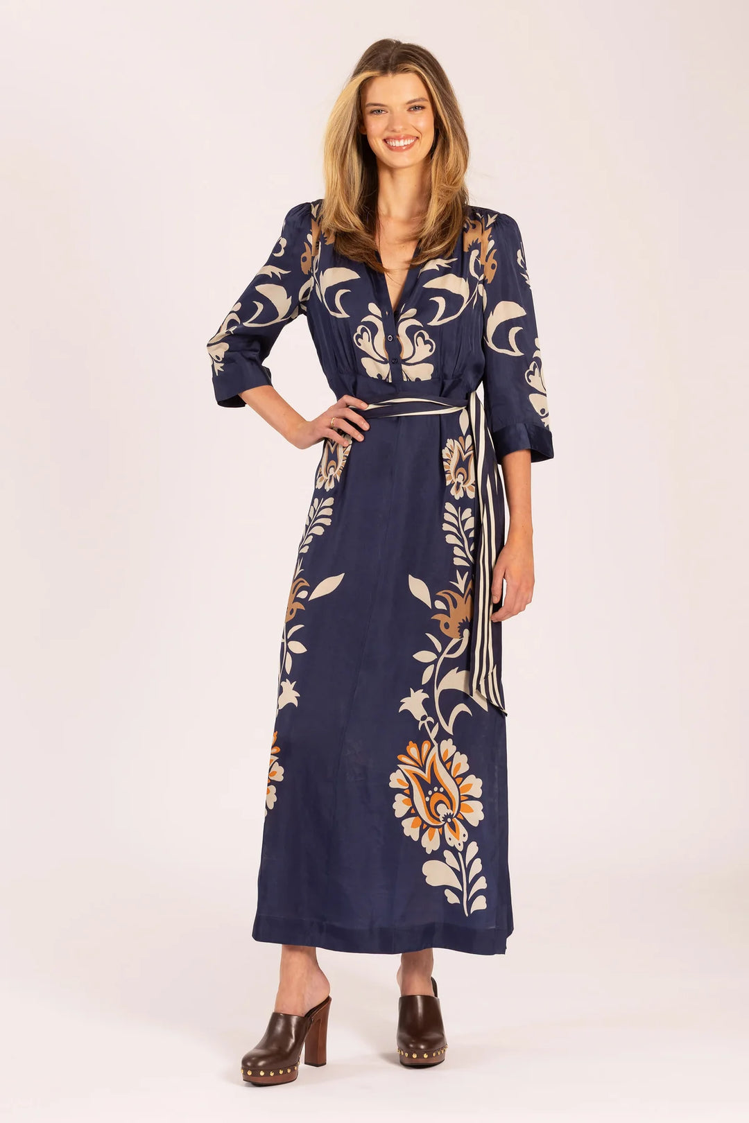 Woman wearing a navy blue dress with floral patterns on a white background