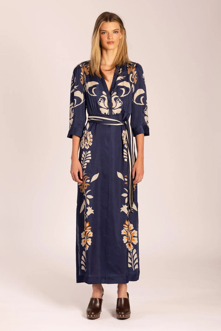 Woman wearing a navy dress with floral patterns on a beige background