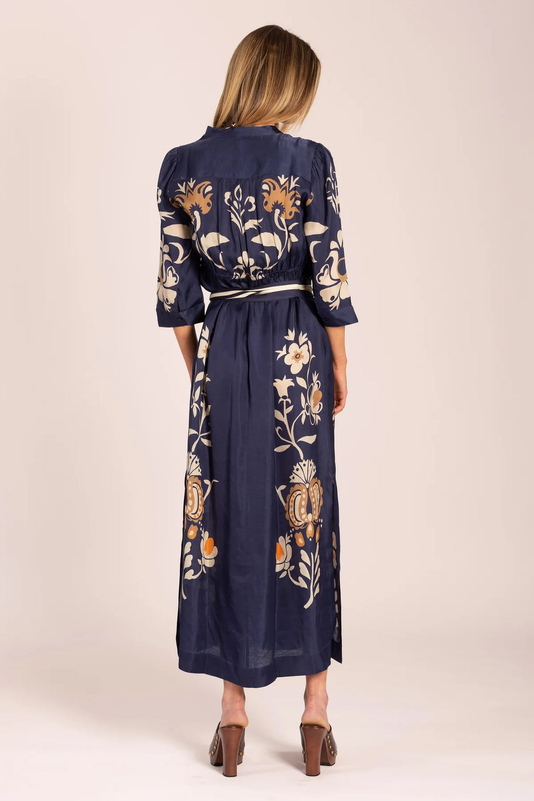 Navy dress with floral patterns worn by a person on a beige background